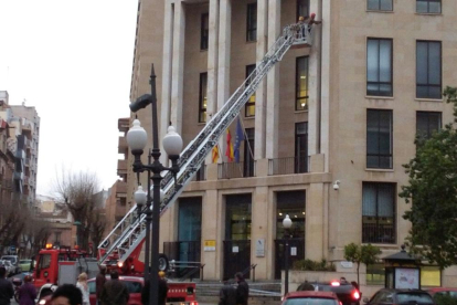 Una dotación de bomberos ha 'saneado' la fachada del edificio de hacienda.