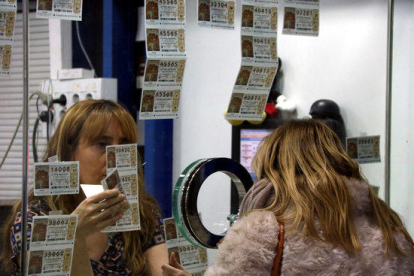 Primer pla de la treballadora d'una administració de loteria amb una clienta comprant un dècim el 19 de desembre de 2016
