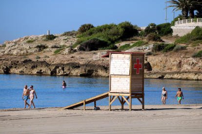 Una torre d'intervenció immediata de la Creu Roja a la platja de l'Arrabassada de Tarragona, i banyistes passejant i banyant-se al mar, el 13 de juny del 2017