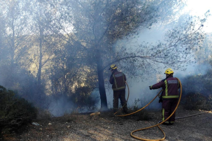 Dos agentes apagando el fuego a Sant Pere i Sant Pau.