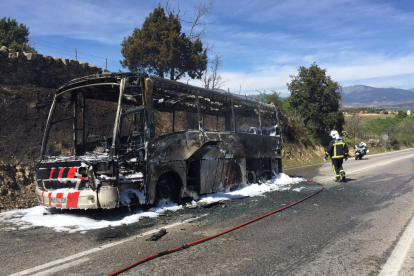 Un efectiu dels Bombers remulla l'autobús calcinat a Guadarrama. pla general del 15 d'abril del 2017