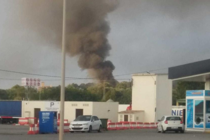 El incendio crea una densa columna de humo negro visible desde lejos.