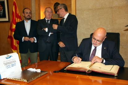 El conseller de Empresa, Jordi Baiget, firmando el libro de honor bajo la mirada del alcalde de Tarragona, Josep Fèlix Ballesteros, el teniente de alcalde Alejandro Fernández y el secretario de Empresa, Joan Aregio.