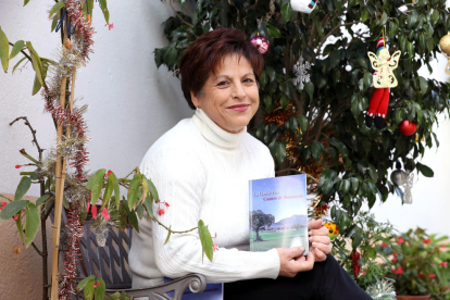 Maria Isabel en la entrada de su casa, con su primer libro, 'La Llama Fría y Cantos de Ausencias'.