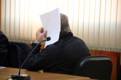 Primer pla de l'acusat tapant-se la cara amb un full de paper a la sala de vistes de l'Audiència de Tarragona.