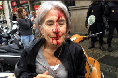 Una mujer con la cara ensangrentada ante|delante de la Escuela Iinfant Jesús de Barcelona, después de una carga policial del 1 de octubre.