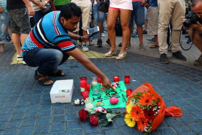 Pla sencer d'un home encenent una espelma a l'ofrena floral del centre de les Rambles el 18 d'agost de 2017