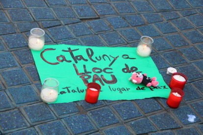 Plano detalle del cartel que con el lema 'Cataluña, lugar de Paz', empieza a acumular flores y velas en recuerdo de las víctimas.