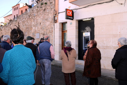 Alguns veïns de Rasquera davant del caixer automàtic del BBVA que no funciona on han llençat un ou. Imatge del 14 de febrer de 20'17 (horitzontal)
