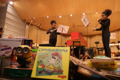 Dos violinistas en el escenario del conservatorio e imágenes de algunos juguetes