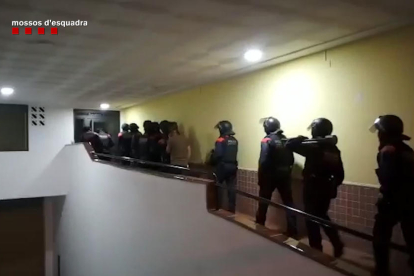 Imagen de los agentes de los Mossos D'Esquadra a punto de realizar una entrada y cacheo durante la operación policial.