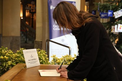 Una dona signa al Llibre de Condol que hi ha a l'entrada a l'edifici de l'Ajuntament.