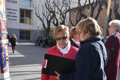 Una agent cívica ofereix informació a una dona que passeja amb el seu gos.