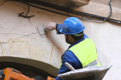 Un operario pone testigos de yeso encima de las grietas aparecidas en la fachada de un edificio.