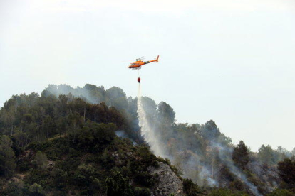 Pla general d'un helicòpter dels Bombers descarregant aigua en un incendi que s'ha originat a Picamoixons, a l'Alt Camp, el 30 de maig del 2017.