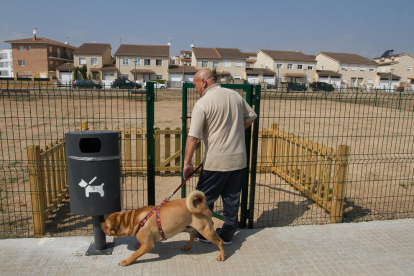 Un home passeja el seu gos en un pipican instal·lat al barri Juroca de Reus.