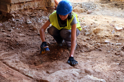 Una arqueòloga excava un mur aparegut davant de l'actual edifici de l'Ajuntament d'Horta de Sant Joan en les obres dels carrers del nucli antic. Imatge del 17 de maig de 2017 (horitzontal)