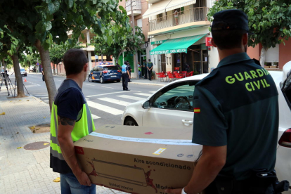 Plano americano de sus agentes de la Policía Nacional y la Guardia Civil transportando en una caja de cartón material intervenido en la operación antidroga que han llevado a cabo en varias poblaciones del Montsià.