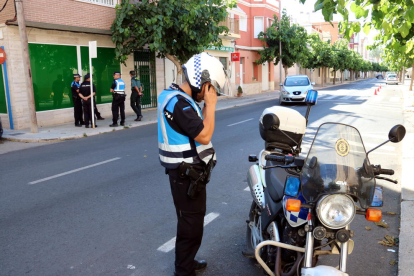 Un agent de la Policia Local d'Amposta amb la seva moto en primer pla amb altres agents al fons custodiant el registre d'un club cannàbic d'Amposta en el marc d'una operació antidroga al Montsià. Imatge del 238 de juny de 2017 (horitzontal)