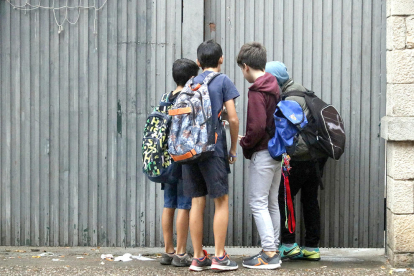 Un grupo de alumnos del colegio Verde de Gerona, comprobando los desperfectos en la puerta de entrada.