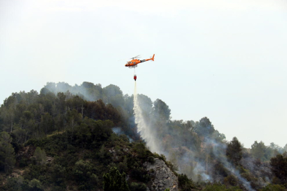 Pla general d'un helicòpter dels Bombers descarregant aigua en un incendi que s'ha originat a Picamoixons, a l'Alt Camp, el 30 de maig del 2017