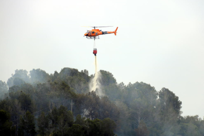 Plano cerrado de un helicóptero de los Bomberos descargando agua en un incendio que se ha originado en Picamoixons, en el Alt Camp, el 30 de mayo del 2017