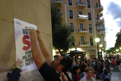 Un participant a l'enganxada col·locant un dels cartells favorables al Sí.