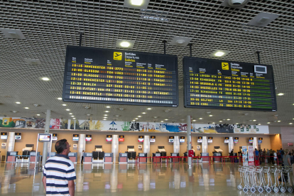 Un usuari consulta les pantalles informatives a l'aeroport de Reus.