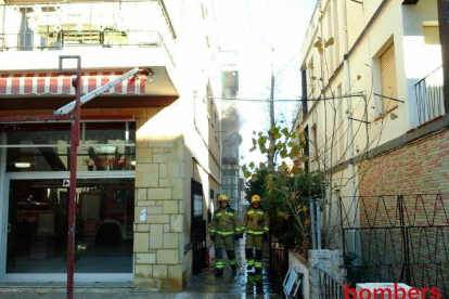 Imatge del pis de Calafell incendiat i dos dels bombers que han intervingut