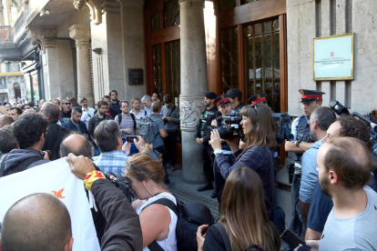 El portal del Departamento de Economía y Finanzas, en la Rambla de Cataluña de Barcelona, custodiado por Mossos y Guardia Civil, lleno de periodistas y ciudadanos con carteles de 'democracia'