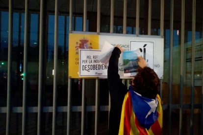 Una manifestante poniendo un cartel anunciando el referéndum en la subdelegación del Gobierno en Tarragona.