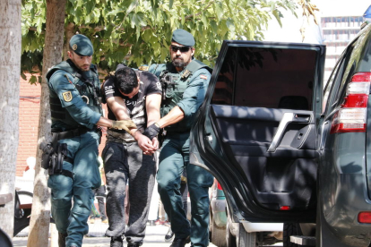 Imagen del chico detenido en Vinaròs, presuntamente relacionado con los atentados de Barcelona y Cambrils, mientras lo trasladan dos agentes de la Guardia Civil al vehículo policial.