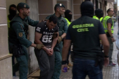 El detingut sortint de la carnisseria familiar per ser traslladat a dependències policials.