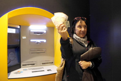 Una dona mostrant els diners que ha tret del caixer seguint la proposta de la Crida per la Democràcia.