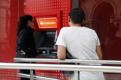 Plano medio de dos personas haciendo cola al cajero del Santander, en la plaza Prim de Reus, el 20 de octubre del 2017.