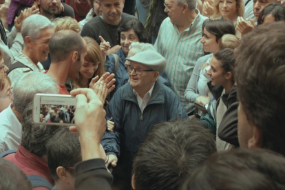 Imatge del documental en la que es veuen desenes de persones i al centre un home gran que avança cap el punt de votació.