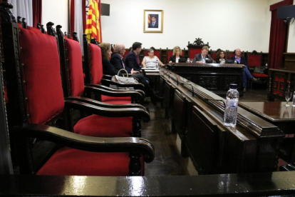 Primer plano de las sillas vacías de los concejales del PSC en el pleno de Tortosa y al fondo la pared donde ha desaparecido la foto del rey Felipe VI.