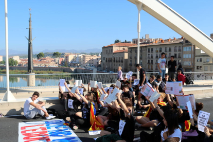 Els estudiants asseguts al pont de l'Estat de Tortosa aixecant llibres en català davant del monument franquista de l'Ebre.