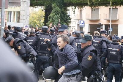 Dos policías se llevan a un hombre de la Escuela Bruguera de Girona.