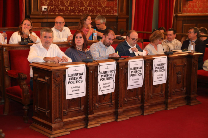 Los concejales de ERC han enganchado cuatro carteles pidiendo 'Libertad presos políticos' ante su fila de asientos.