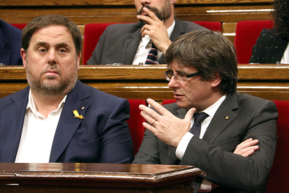 El presidente de la Generalitat, Carles Puigdemont, habla con el vicepresidente, Oriol Junqueras, en el Parlamento