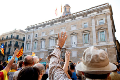Un hombre levantando los cuatro dedos delante de la fachada del Palau de la Generalitat.