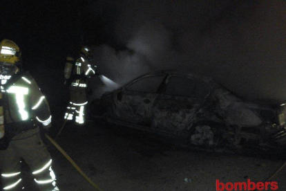 Imatge dels bombers mullant els vehicles cremats per evitar que proliferi el foc