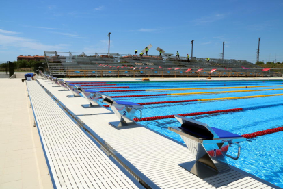 Pla obert de la piscina dels Jocs Mediterranis de Tarragona 2018, amb operaris treballant i els saltadors en primer terme. Imatge del 14 de juny del 2018