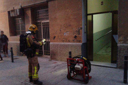 Un bomber, amb un ventilador a la porta de l'immoble.