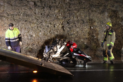 Els serveis d'emergències retiren la moto que ha quedat destrossada després de l'impacte