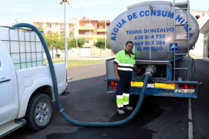 Pla general d'un operari de la Brigada Municipal de Móra la Nova omplint una cisterna del camió dipòsit que s'ha ubicat al pavelló per abastir els veïns d'aigua potable. Imatge del 28 de juny de 2018 (horitzontal)