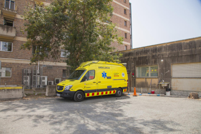Imatge d'ahir al migdia de l'ambulància amb base a l'hospital Joan XXIII aparcada sota un arbre.
