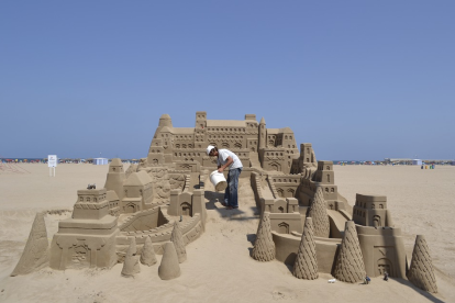 Imagen de archivo de un hombre construyendo un castillo de arena.