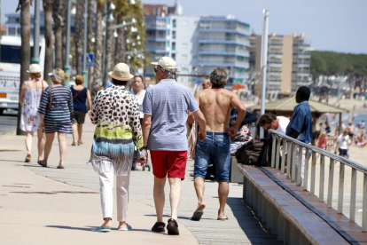 Plan general de varios turistas paseando por el paseo marítimo de la playa de la Pineda, en Vila-seca, el 9 de mayo del 2018